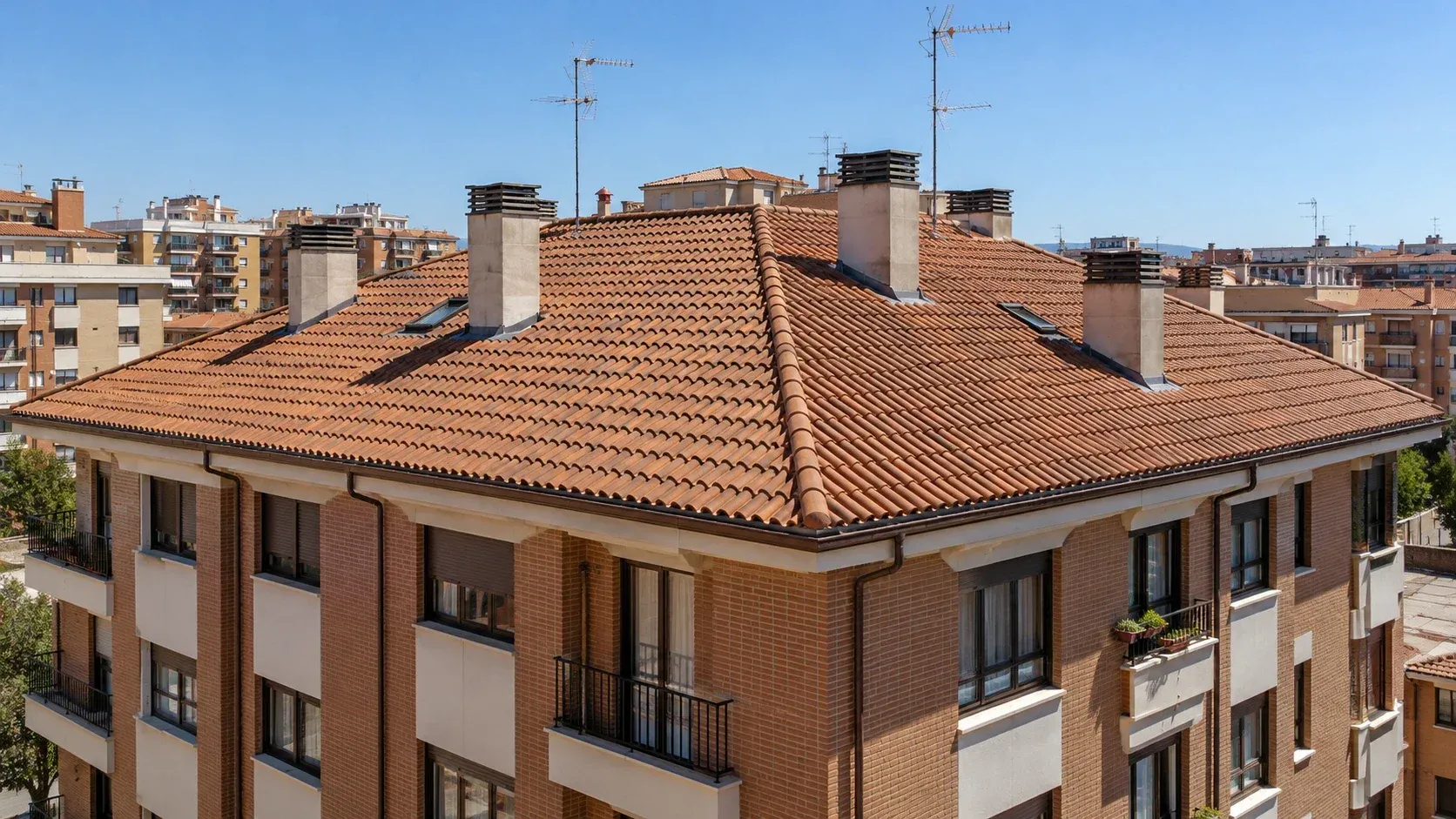 Tejado de teja de un edificio de viviendas de ladrillo con chimeneas y antenas
