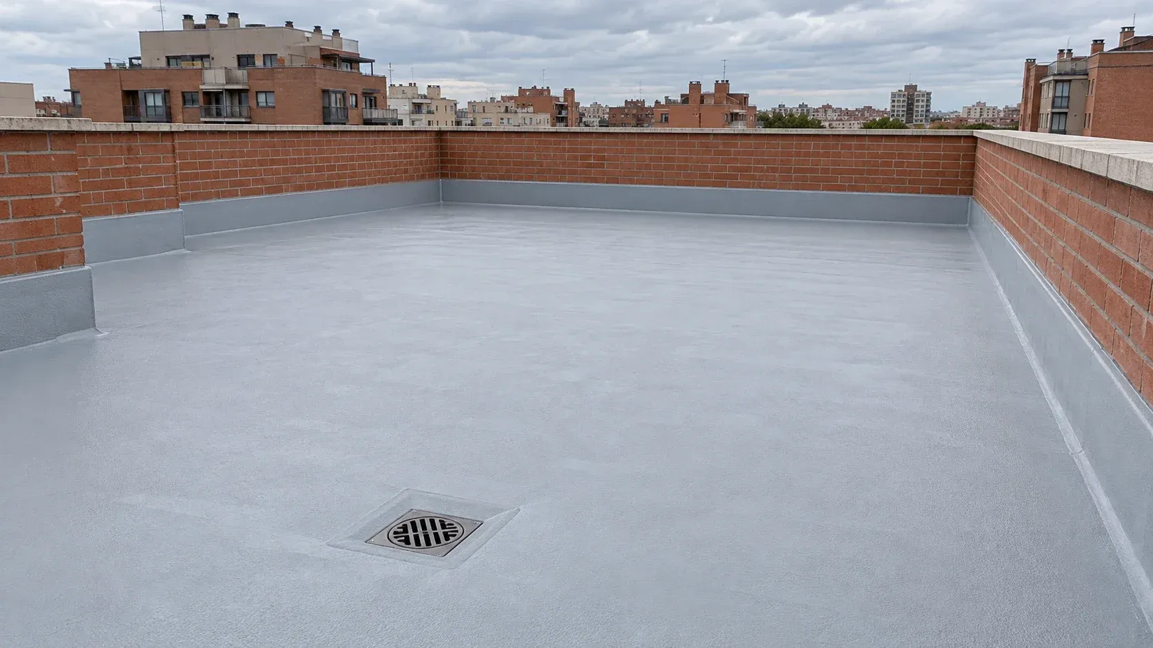 Terraza plana de un edificio recién impermeabilizada con membrana gris rematada en los petos